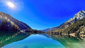 Un lago tranquilo rodeado de montañas bajo un sol brillante.