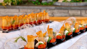 A buffet table with various appetizers, including spring rolls and a glass dish with a red sauce.