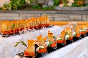 A buffet table with various appetizers, including spring rolls and a glass dish with a red sauce. - Hotel Chalet Olympia (Monguelfo)
