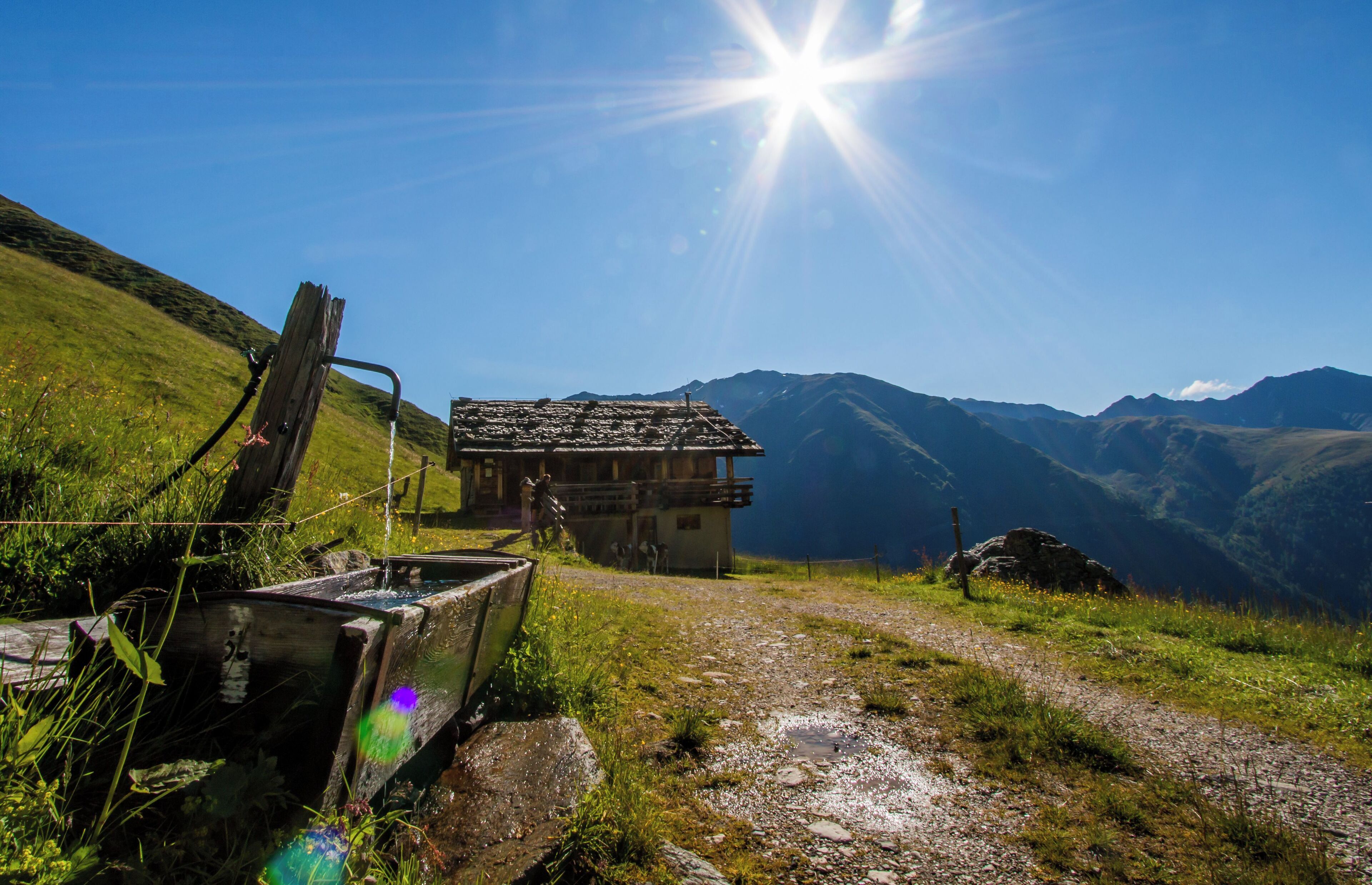 A mountain path leading to a rustic cabin with a clear view of the surrounding hills.