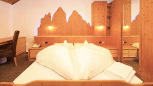 Un dormitorio de madera con una cama, un escritorio y un aparador.