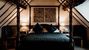 Une chambre à coucher avec un lit à baldaquin, deux lampes de chevet, une table de chevet et un tableau au mur.