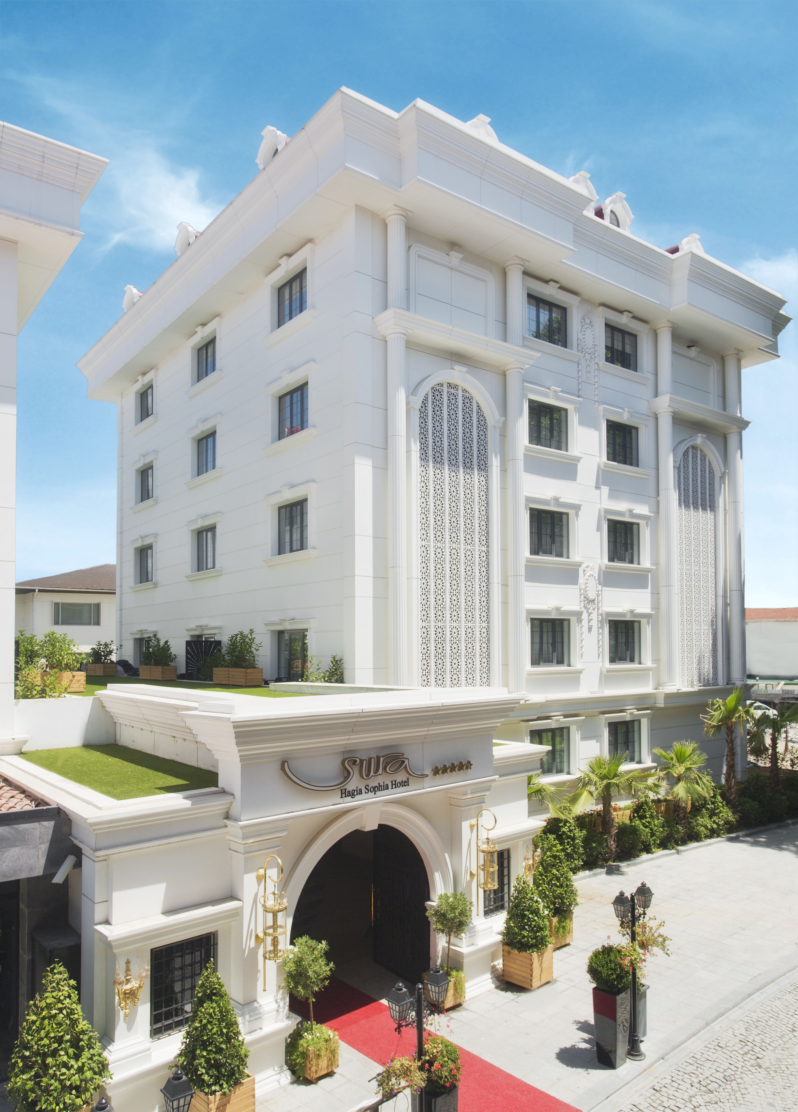 A white building with a red carpet entrance, columns, and a sign reading "Hagia Sophia Hotel".
