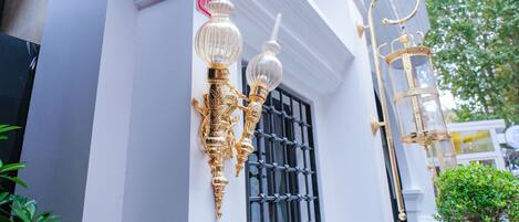 A building with ornate gold and glass wall sconces and a decorative lantern.