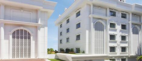 Un edificio blanco con una entrada central, ventanas amplias y un letrero que dice "Hagia Sophia Hotel".