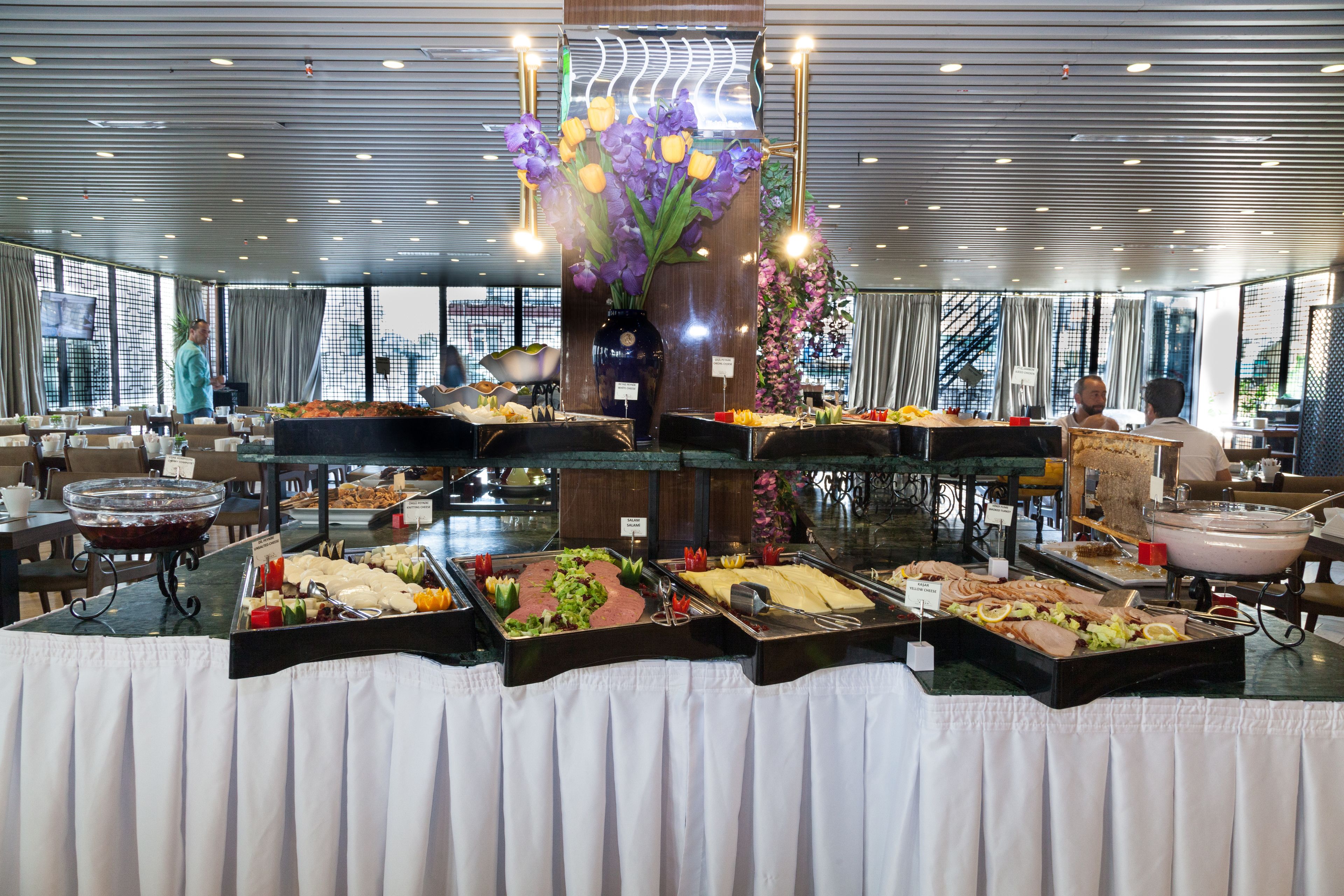 A buffet with various food options, a large vase with flowers, and a modern interior design.