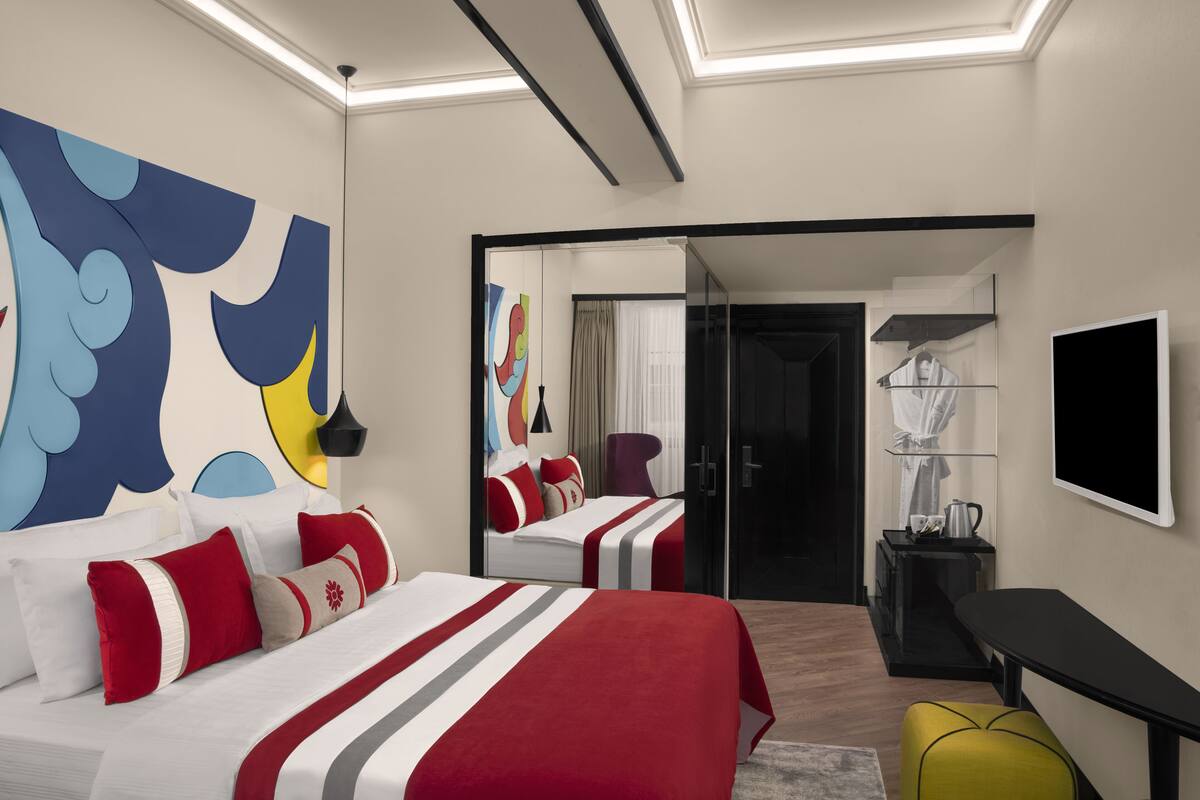 Una habitación de hotel moderna con una cama grande, un escritorio, una silla y un televisor.