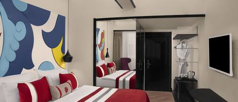 A modern hotel room with a large bed, a desk, a chair, and a TV.