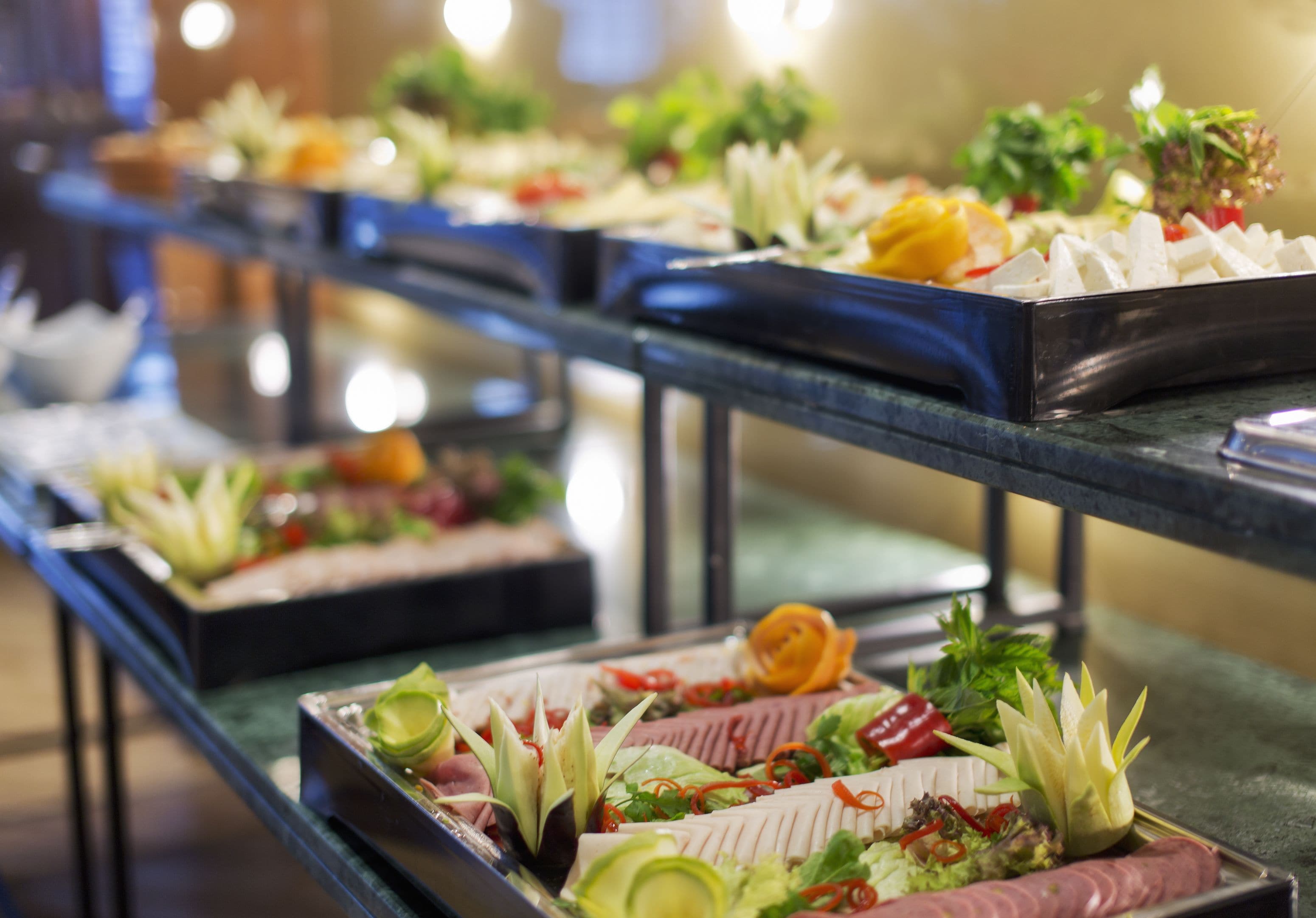 A buffet with various dishes, including meats and vegetables, arranged on metal trays.