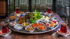 Een saladebar met diverse groenten en een schaal met gerechten, waaronder olijven, tomaten en kaas.