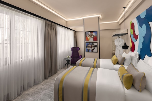 Habitación de hotel con dos camas, una silla morada, una mesita con un florero y obras de arte en las paredes.