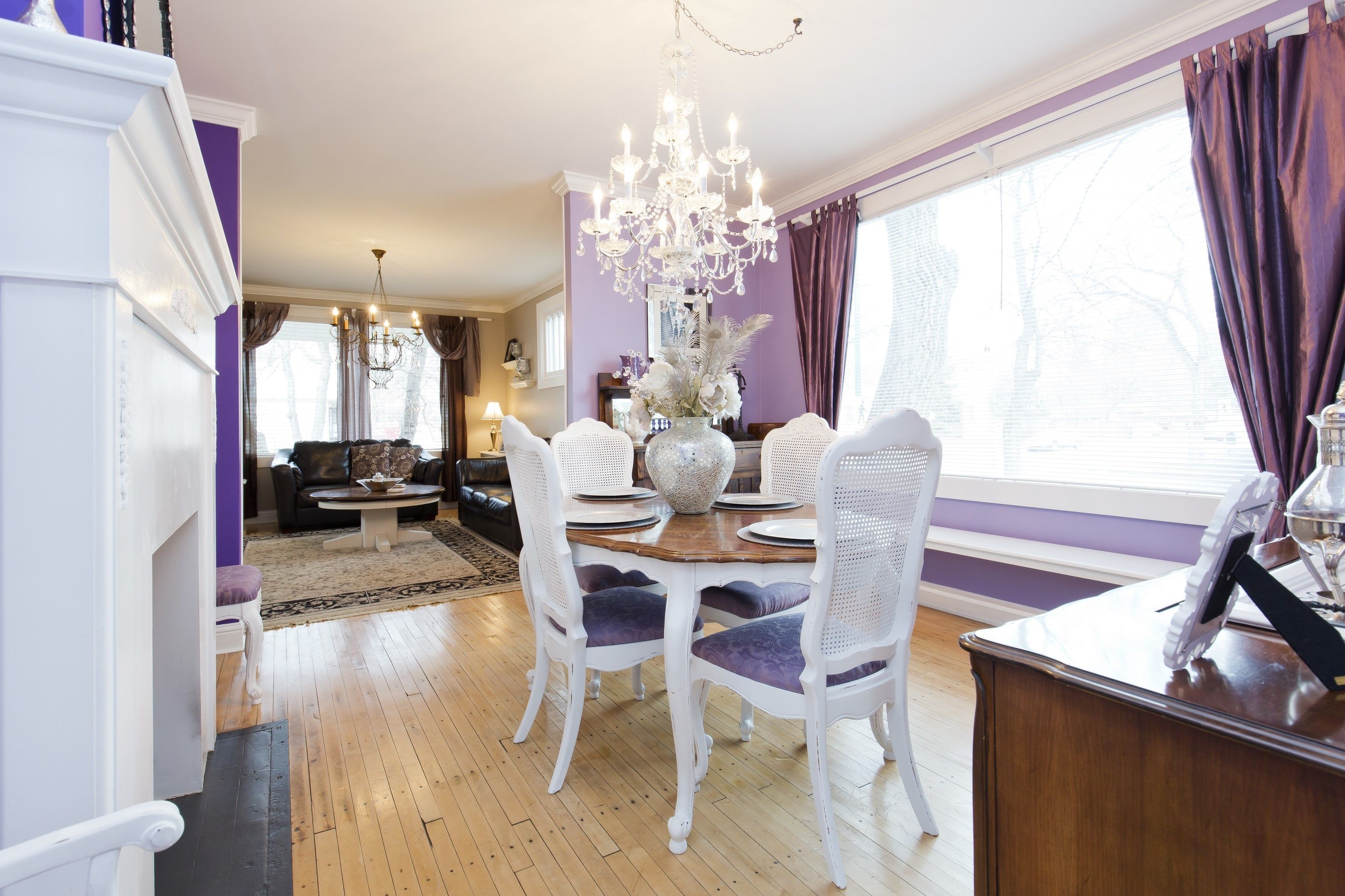 A dining area with a chandelier, white chairs, and a wooden table.