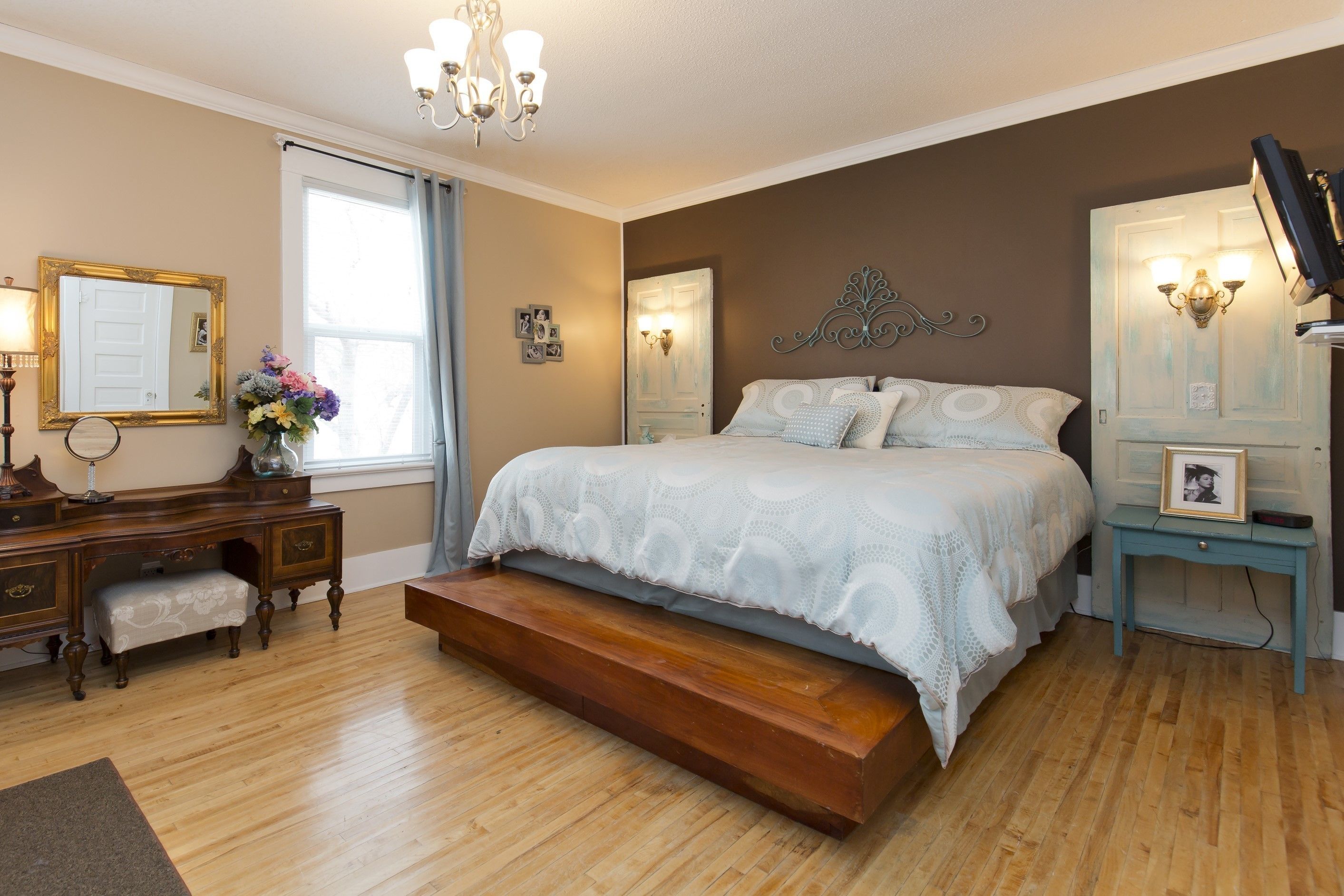 A bedroom with a large bed, wooden dresser, and a desk.