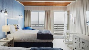 Ein Hotelzimmer mit Bett, Nachttisch, Lampe und Blick auf einen Balkon.