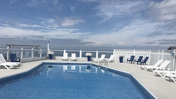 Una piscina al aire libre de temporada, tumbonas
