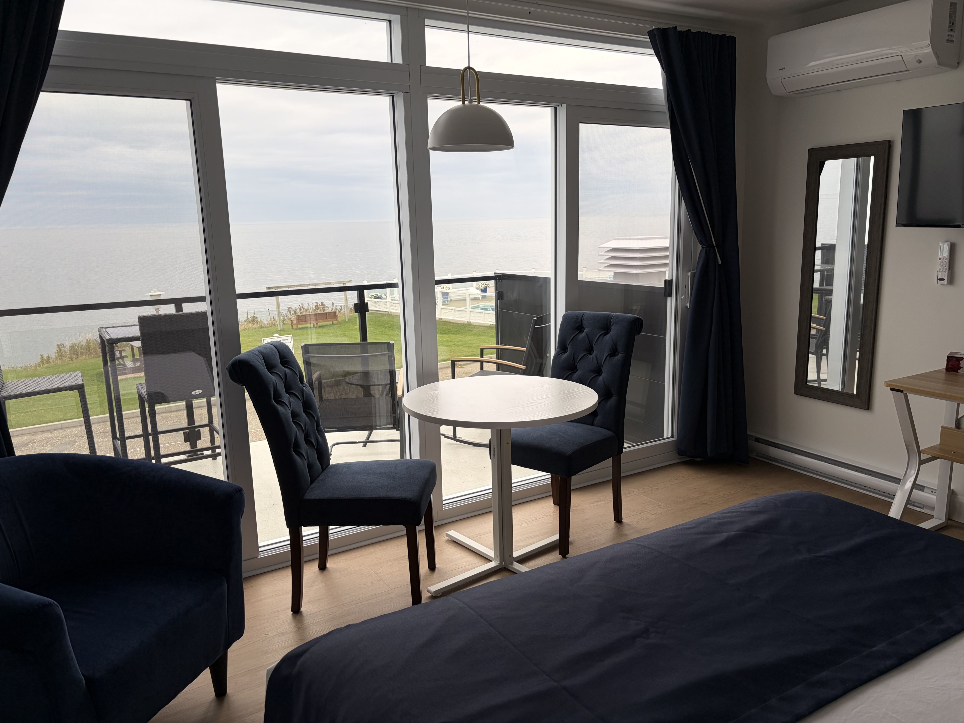 Een hotelkamer met balkon, een ronde tafel, twee stoelen, een bed en een televisie.