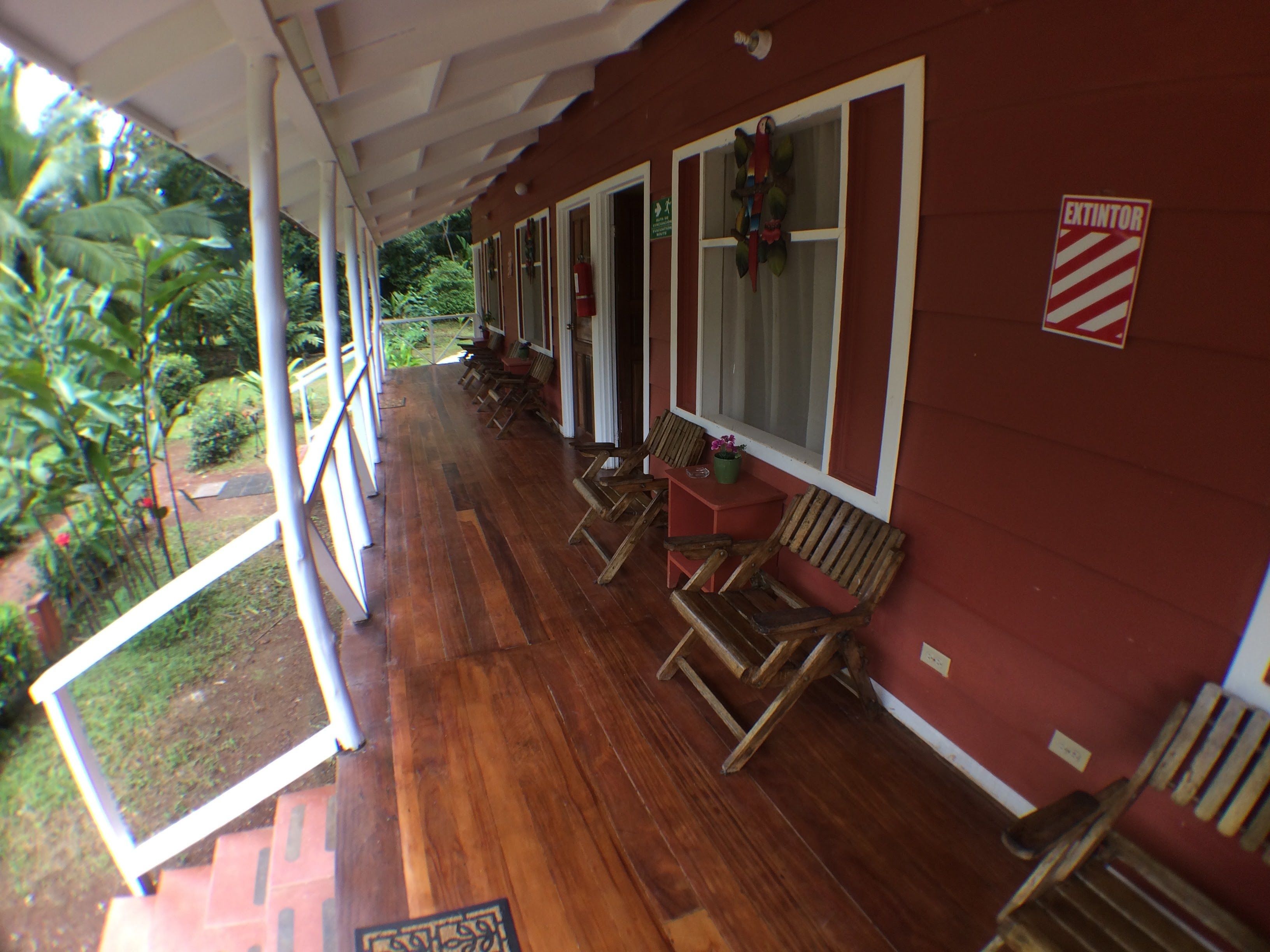 A covered porch with wooden benches and a red exterior wall.