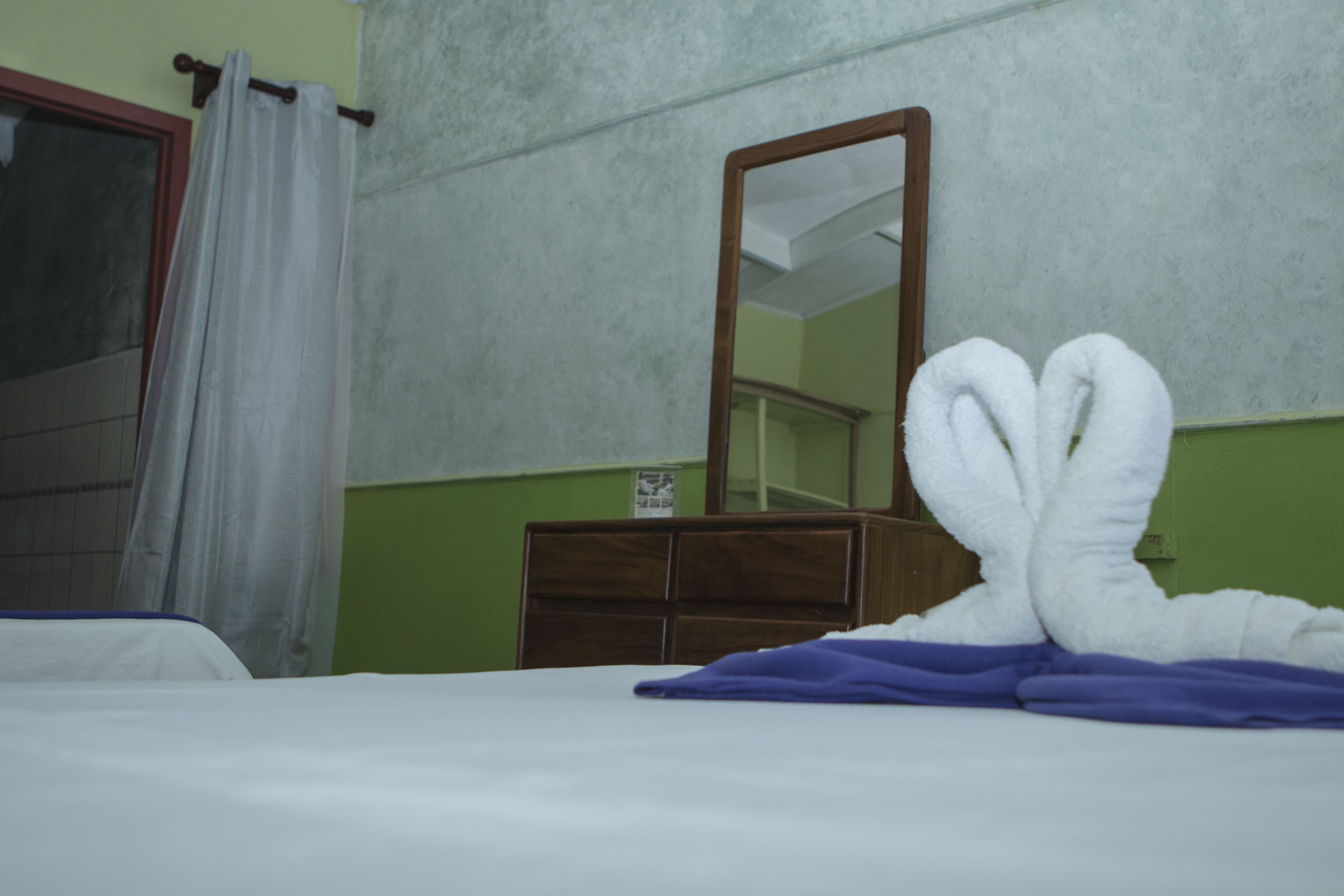 A hotel room with a bed, a dresser, and a mirror.