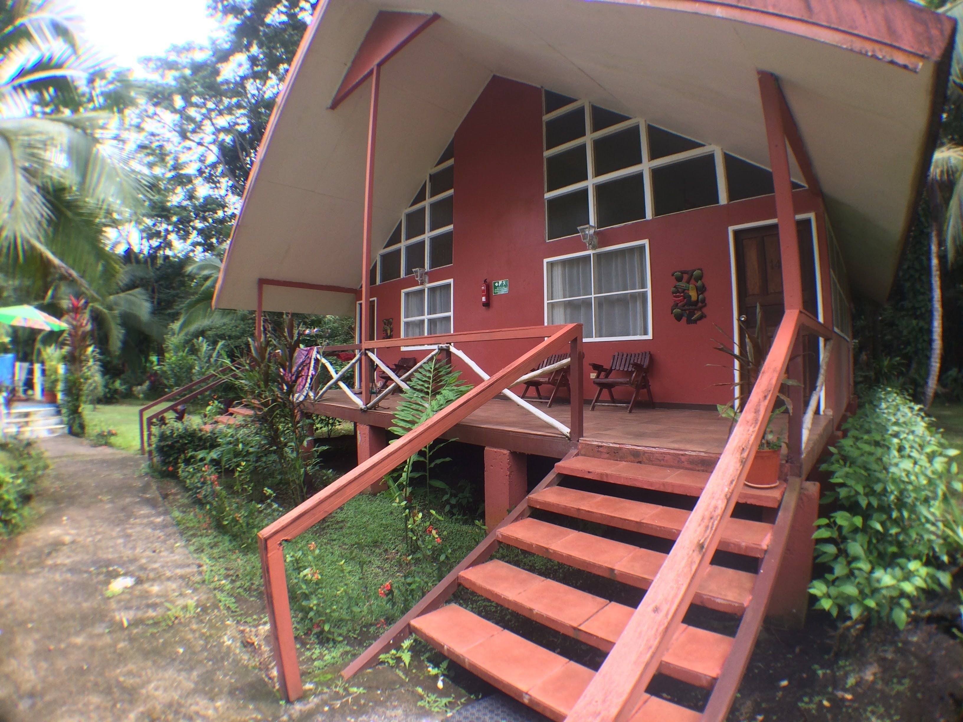A house with a sloped roof, a porch with wooden steps, and a garden area with plants and a pathway.