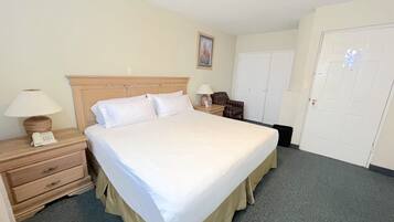 Une chambre d’hôtel avec un grand lit, une table de chevet avec une lampe, une chaise et une armoire.