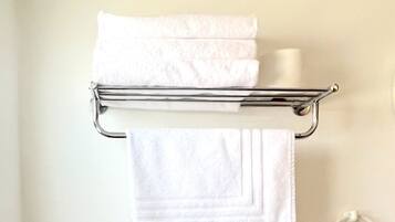 Une salle de bain équipée de toilettes, d’une poubelle et d’un porte-serviettes avec des serviettes pliées.