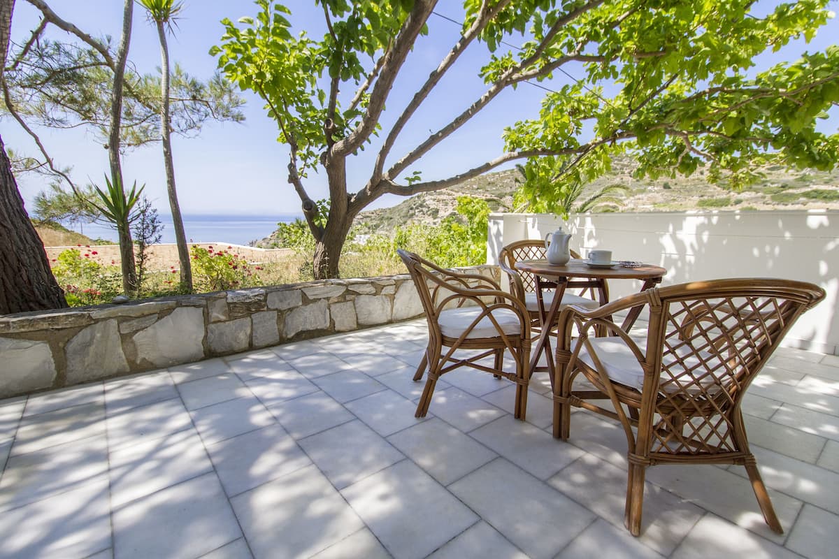 A patio with wicker furniture and a view of the sea.