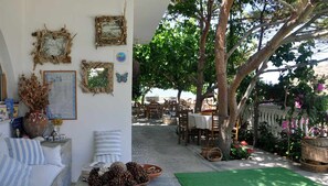 A cozy outdoor seating area with rustic decor, including a table set for dining and a comfortable seating arrangement. - Petrino (Naxos)