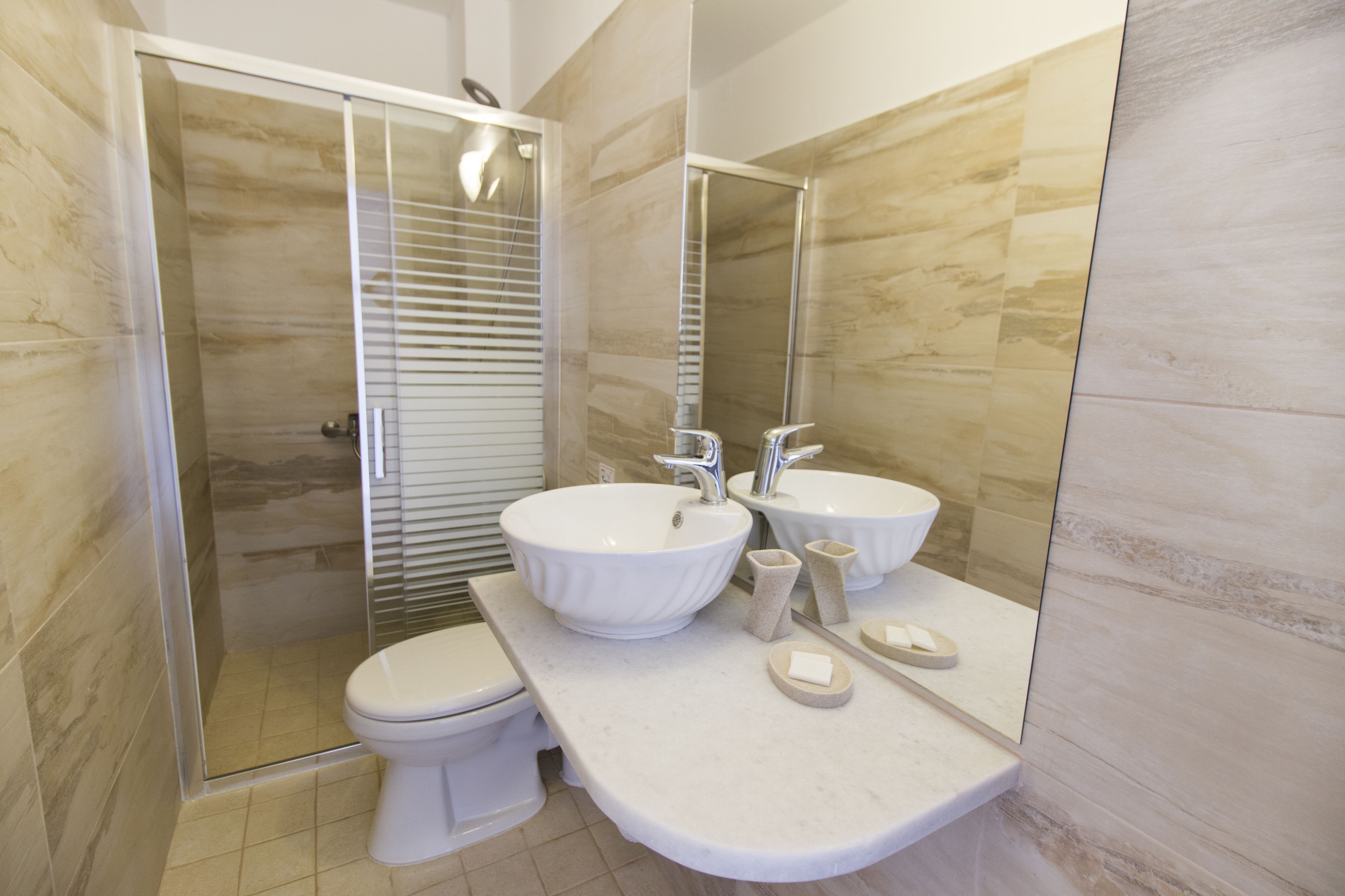 A modern bathroom with a glass-enclosed shower, two sinks, and a toilet.