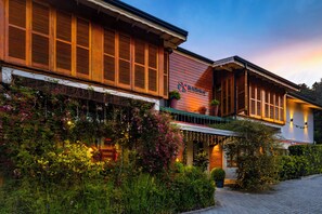 Un edificio con fachada de madera, un letrero que dice 'Británico' y un jardín con plantas e iluminación.