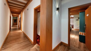 A hallway with wooden beams, a red chair, and a teal door. - Hotel Boutique Britânico (Gramado)