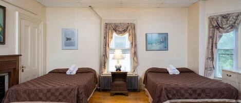 A hotel room with two beds, a fireplace, and a large window with curtains.