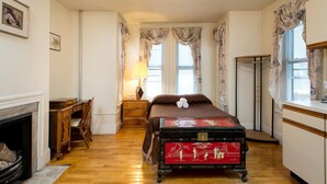 A bedroom with a bed, a dresser, a desk, a lamp, and a fireplace. - The Farrington Inn (Boston)
