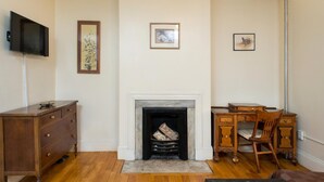 A room with a fireplace, wooden furniture, and artwork on the walls. - The Farrington Inn (Boston)
