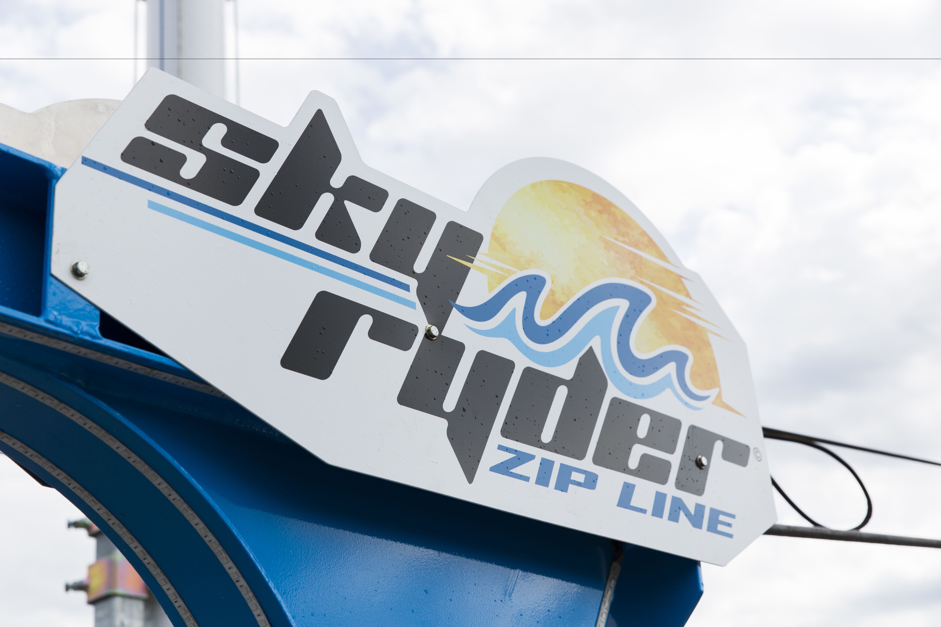 Et skilt med teksten 'Sky Rider ZIP LINE'.