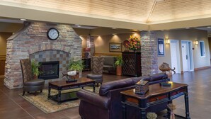 A spacious lobby with a stone fireplace, leather seating, and a high wooden ceiling. - Bridges Bay Resort (Arnolds Park)