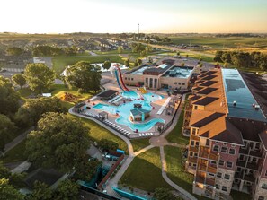 A residential area with a swimming pool, a water slide, and a building with a flat roof. - Bridges Bay Resort (Arnolds Park)
