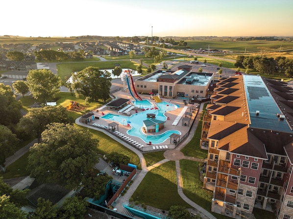 A residential area with a swimming pool, a water slide, and a building with a flat roof. - Bridges Bay Resort (Arnolds Park)