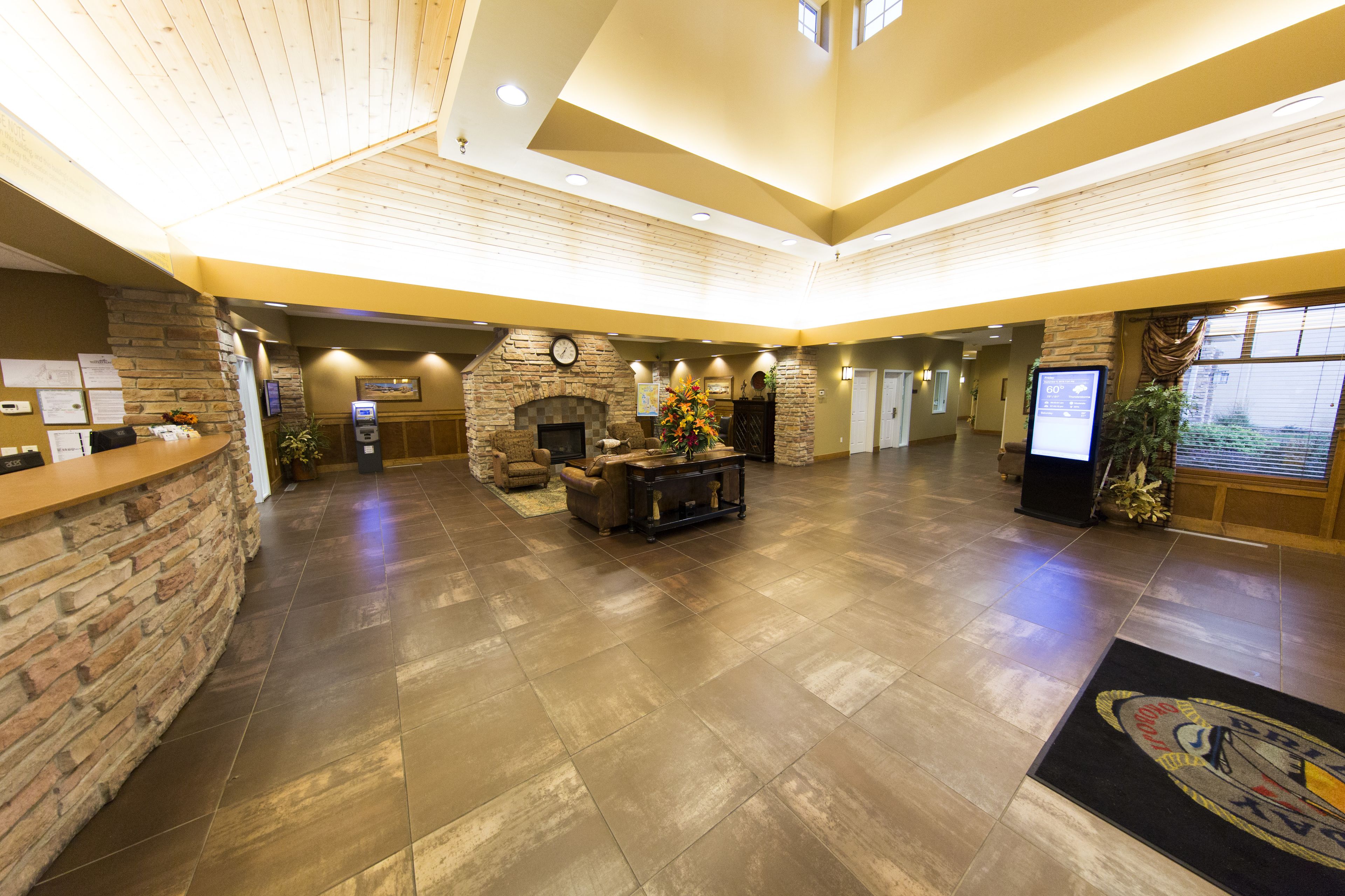 A spacious lobby with a stone fireplace, a reception desk, and a large screen.