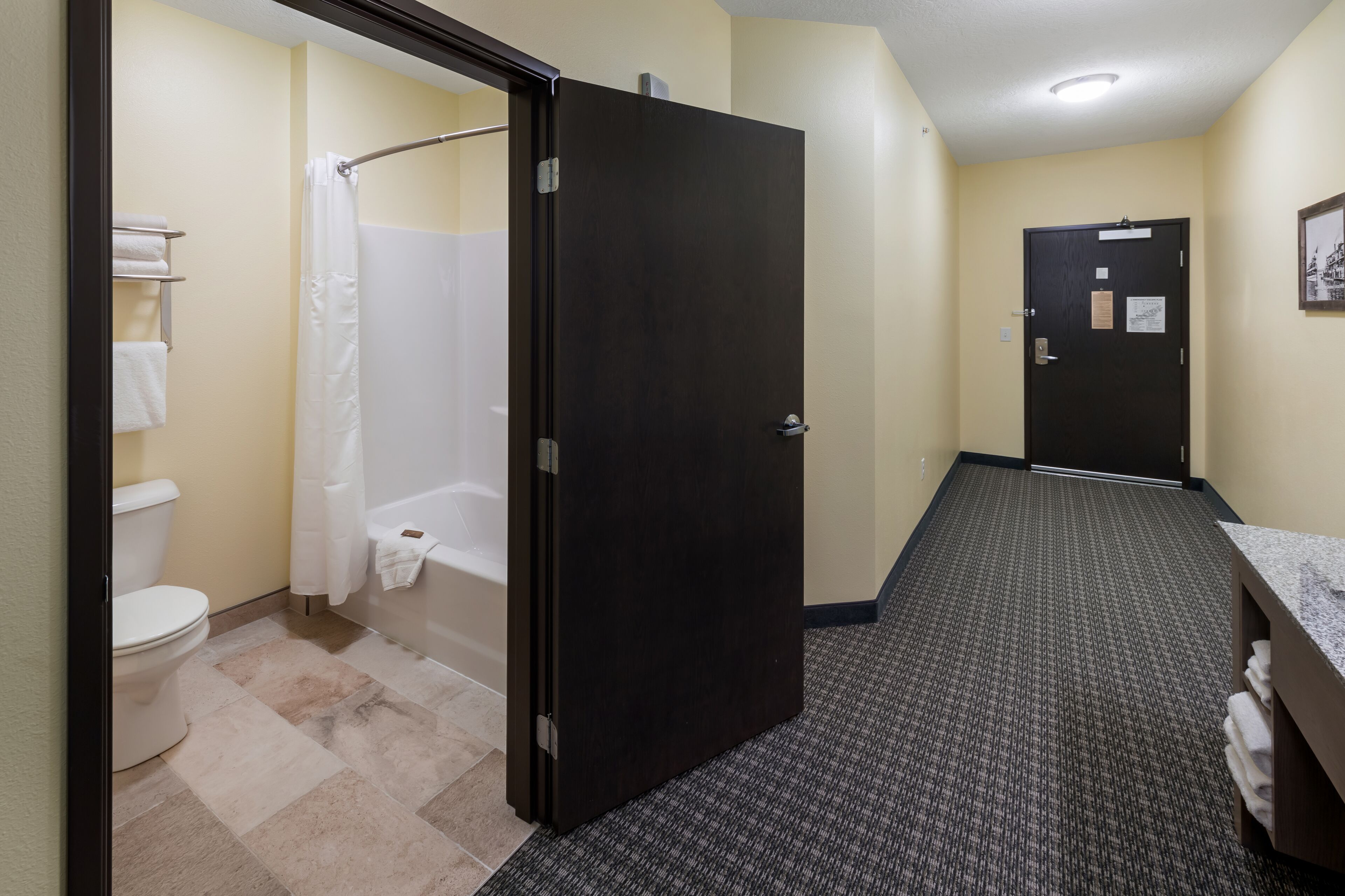 Une salle de bain d’hôtel équipée de toilettes, d’une douche et d’un lavabo, ainsi que de serviettes.