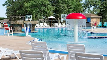 A swimming pool with lounge chairs, a water fountain, and a basketball hoop.