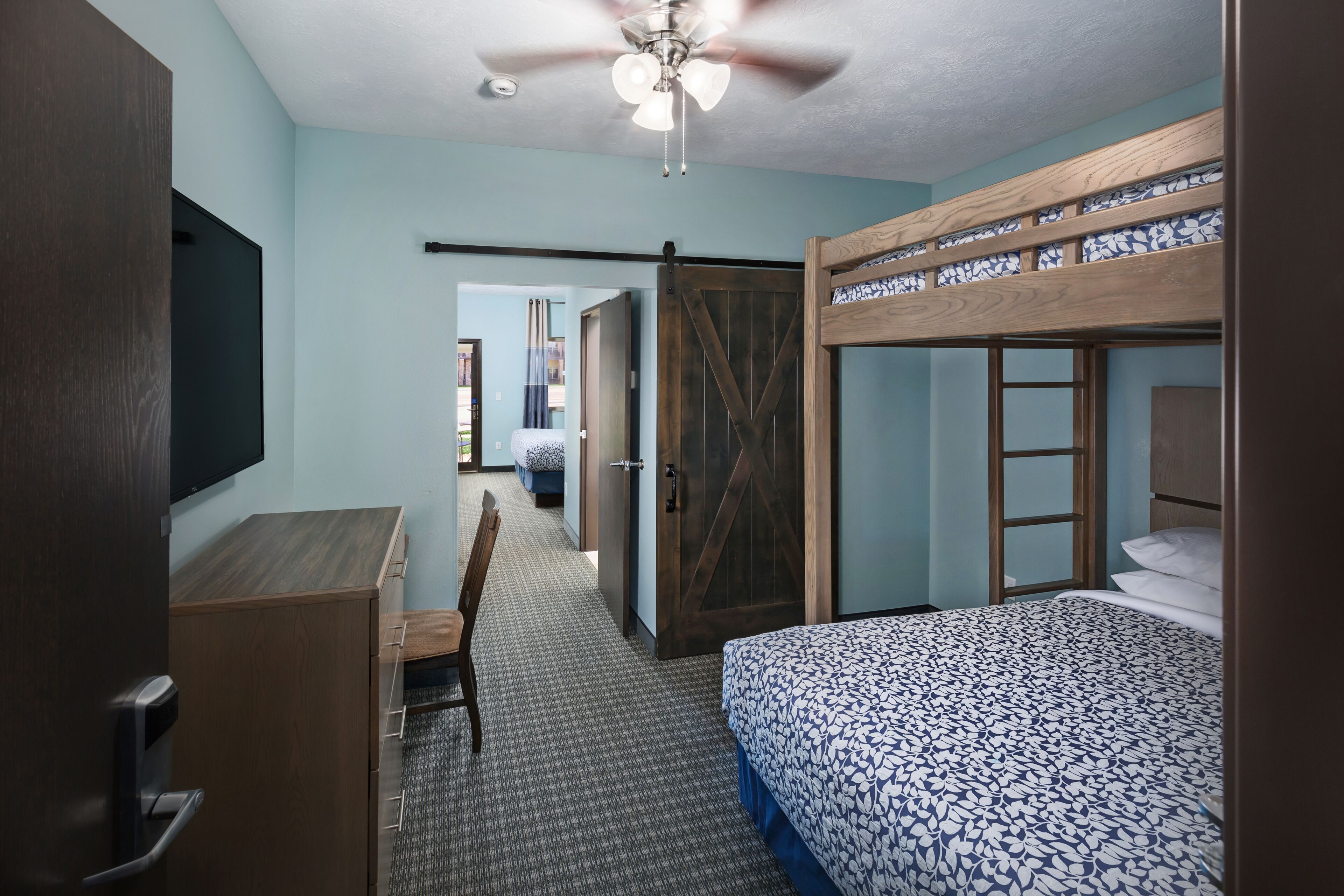 A bedroom with a bunk bed, a desk, and a chair.