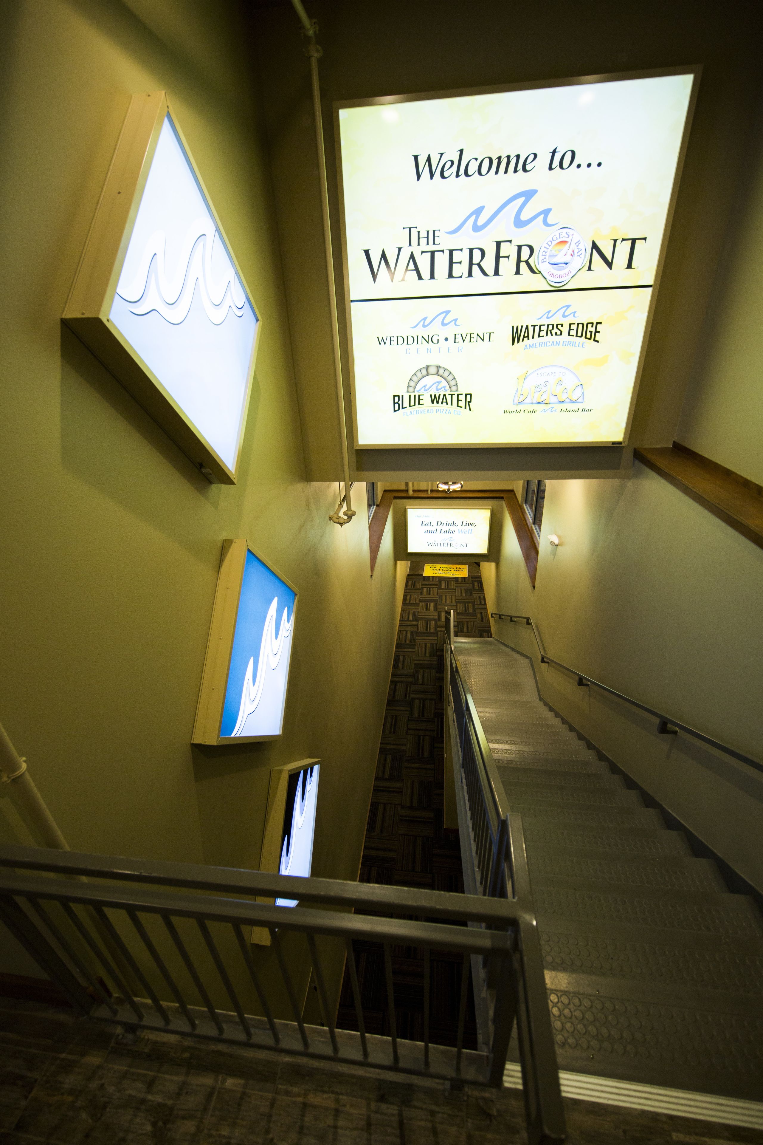 En trappa leder upp till ett receptionsområde med en stor välkomstskylt för evenemanget ”The Waterfront”.