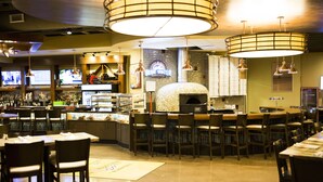 A restaurant with a bar area, multiple seating arrangements, and a visible pizza oven. - Bridges Bay Resort (Arnolds Park)