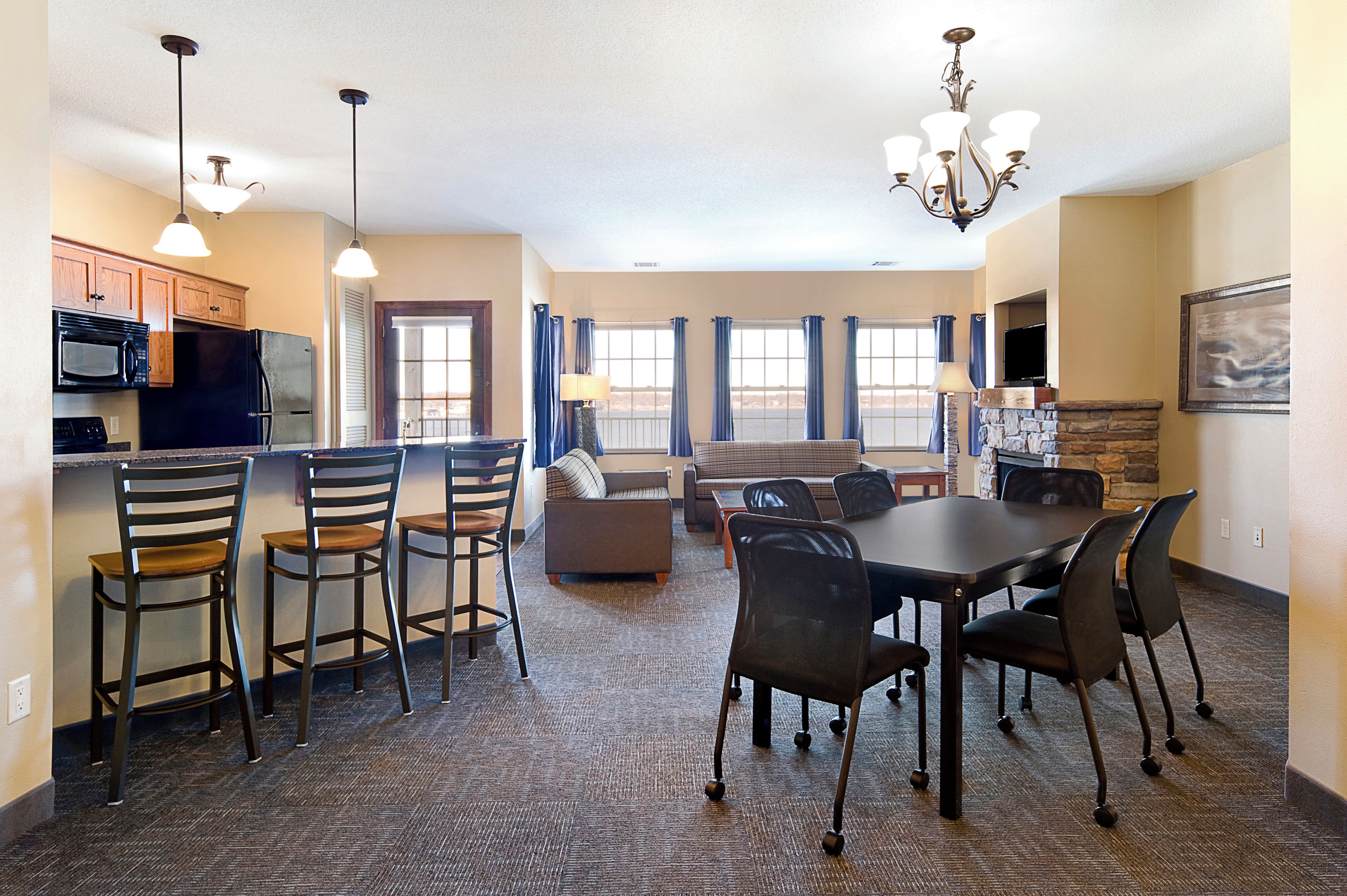 A modern kitchen with built-in appliances, a dining area with a table and chairs, and a living room with a sofa and a television.