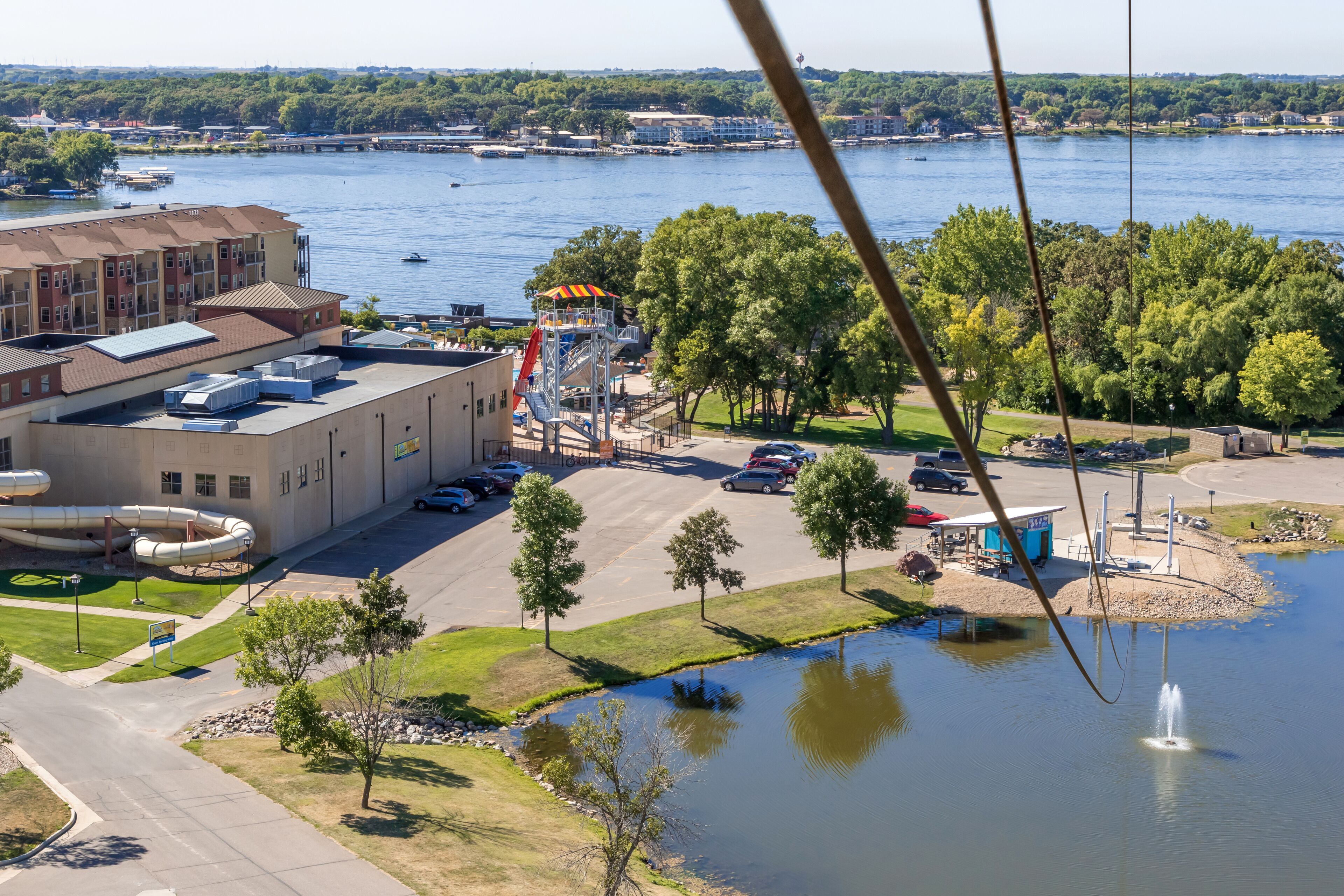 En vy över en vattenpark med en byggnad, en parkeringsplats och en sjö.
