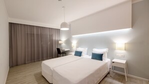 A modern hotel room with a large bed, bedside tables, a desk, and a chair. - Alvormar Apartamentos Turísticos (Portimão)