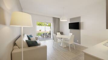 A modern living room with a sofa, a dining table, and a TV mounted on the wall.