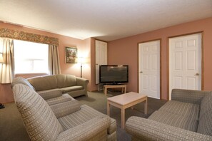 A living room with a sofa set, a television, and a lamp. - Bow River Inn (Cochrane)