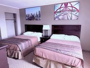 A hotel room with two beds, a nightstand, a lamp, and two paintings on the wall. - Premium Inn & Suites Calgary Airport (Calgary)