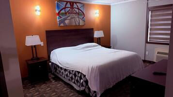 A hotel room with a bed, two bedside lamps, a painting on the wall, and a window with blinds.